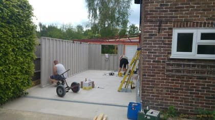 Nucrete team preparing a freshly laid concrete garage base beside a house
