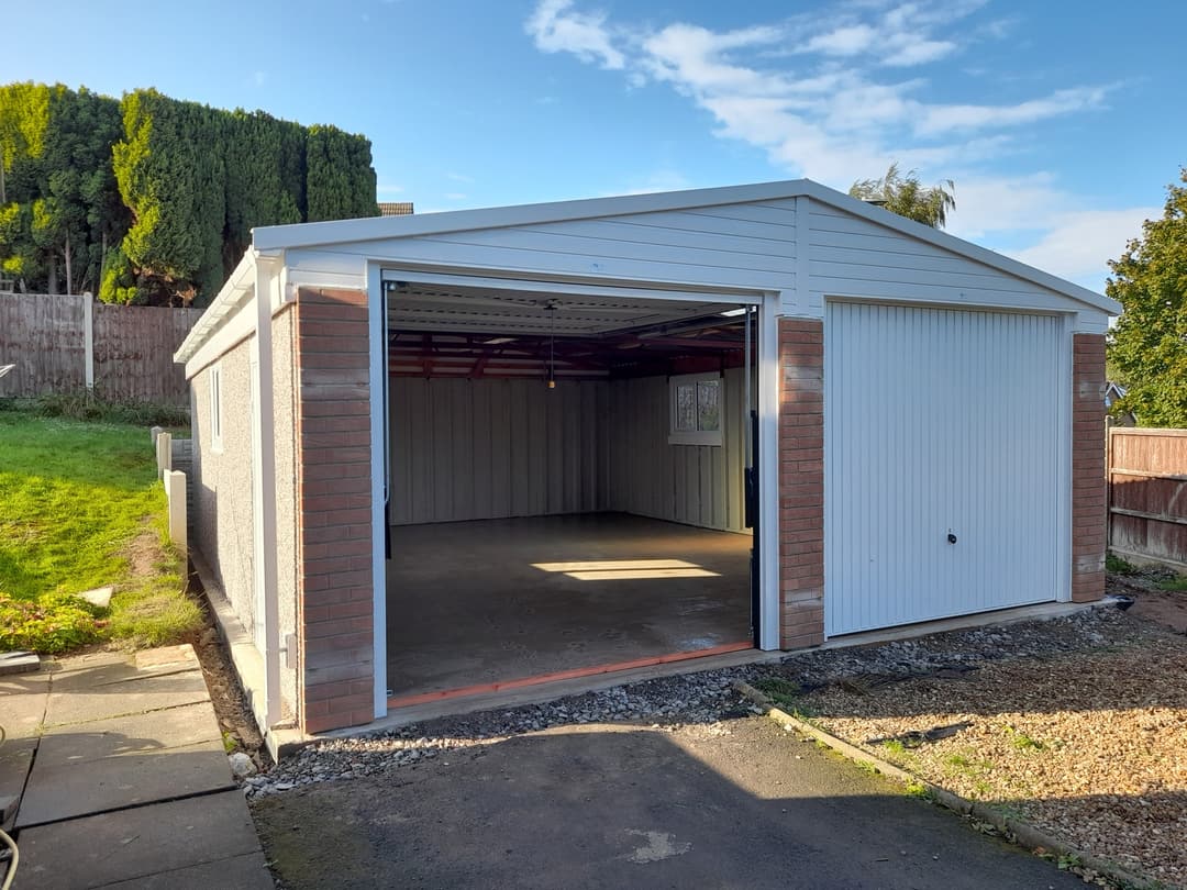 Nucrete double apex concrete garage with brick-effect front and two white up-and-over doors, newly installed at a UK home